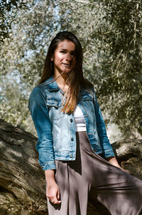 Portrait of smiling young woman standing against trees