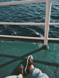 Low section of woman on railing by sea