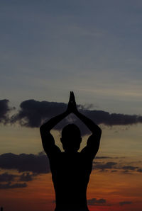 Silhouette woman with arms raised against sky during sunset