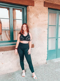 Full length portrait of woman standing against window