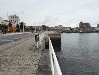 View of buildings by sea against cloudy sky