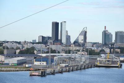 Buildings by river against sky in city