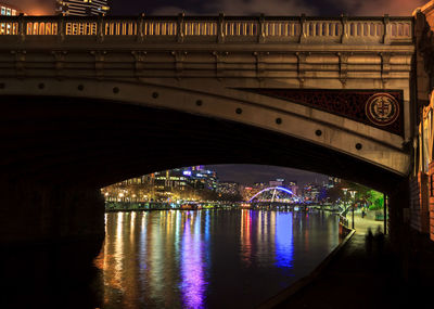 Illuminated bridge over river at night