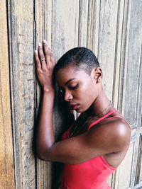 Close-up of young woman leaning on wooden wall