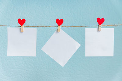 Close-up of multi colored flags hanging on rope against white wall