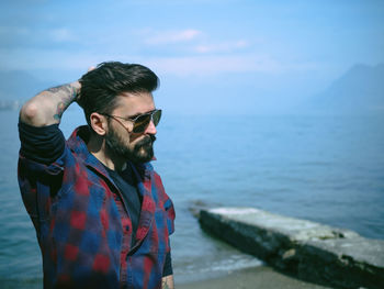 Close-up of man wearing sunglasses at beach against sky