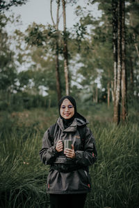 Portrait of smiling young woman standing on field