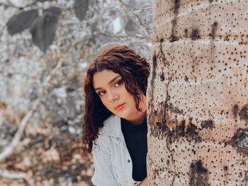 Portrait of a young woman behind a tree