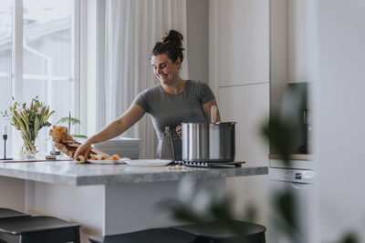 Smiling woman in kitchen preparing food