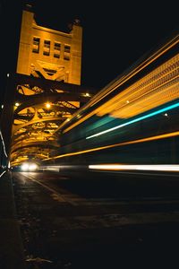 Light trails on road in city against sky at night