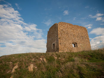 Low angle view of old ruin on field against sky