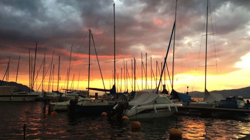 Sailboats moored at harbor during sunset