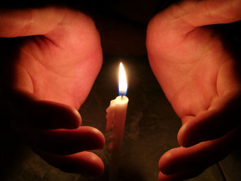 Close-up of person holding burning candle