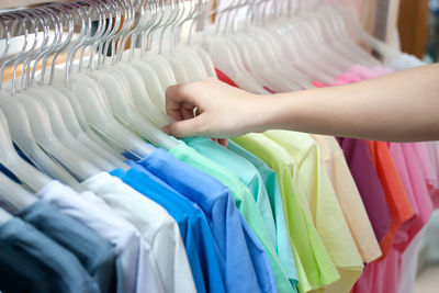 Cropped hand holding of cloth in rack for sale in store