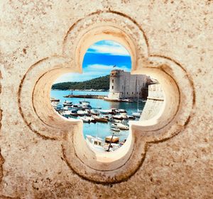 Boats moored on sea seen through floral pattern in wall