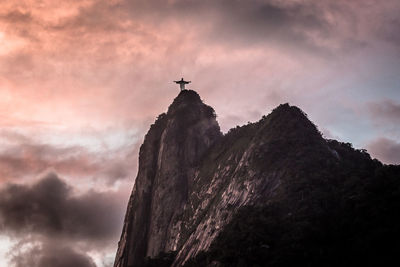 Low angle view of cliff against cloudy sky