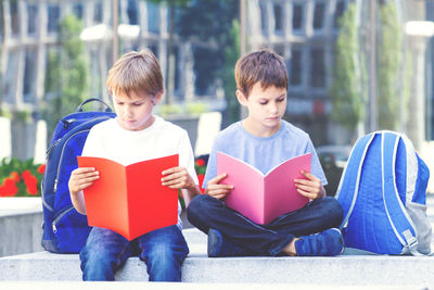 Friends reading books while sitting on steps