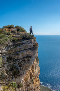 A men on a cliff facing the mediterranean sea