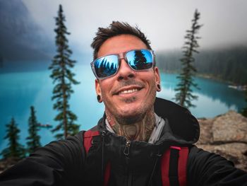 Portrait of young man wearing sunglasses against trees