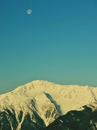 Scenic view of snowcapped mountains against clear blue sky