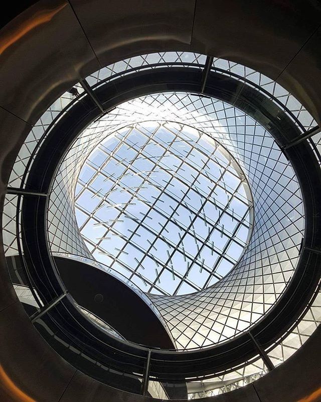 indoors, architecture, built structure, window, pattern, glass - material, skylight, modern, geometric shape, design, ceiling, architectural feature, transparent, low angle view, arch, building, circle, repetition, railing, no people