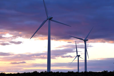 Low angle view of wind turbine against sky during sunset