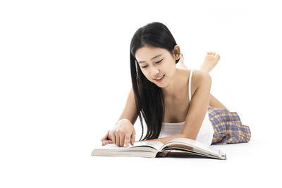 Young woman reading book against white background