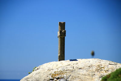 Low angle view of old wooden post against clear blue sky