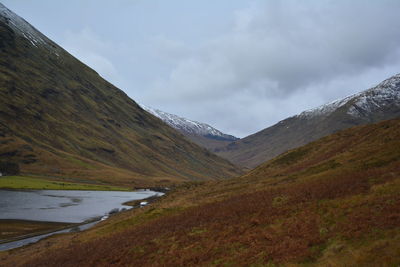 Scenic view of lake by mountains against sky