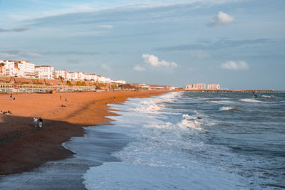 People walking down the promenade near the beach in brighton.