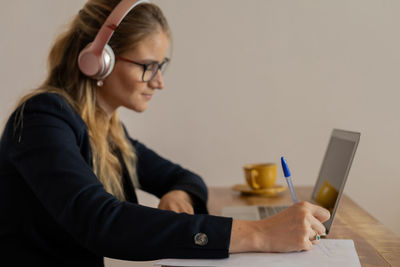 Woman working at home with laptop and papers on desk and headphones. home office . gray notebook 