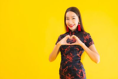 Portrait of a smiling young woman against yellow background