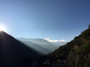 Cars on road at mountains against blue sky