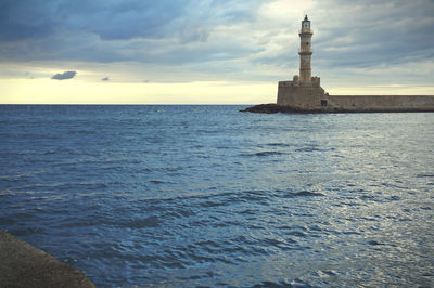 Chania lighthouse by sea against cloudy sky