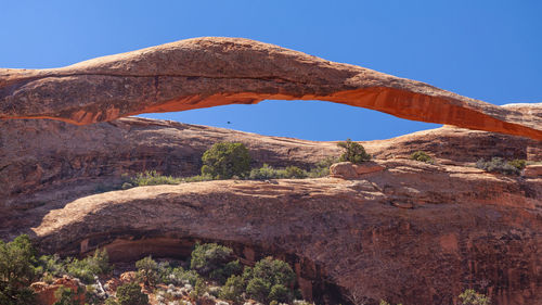 Low angle view of rock formation against clear blue sky