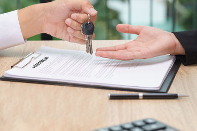 Cropped image of man holding paper with text on table