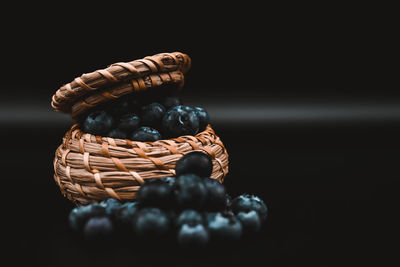Close-up of fruits in basket on table against black background