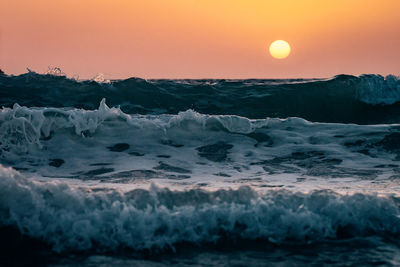 Scenic view of sea waves against sky during sunset