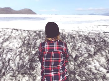 Rear view of woman standing by glacier at winter