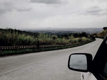 Road by trees against sky seen through car windshield