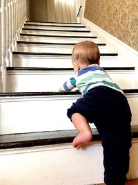 Rear view of boy with umbrella on staircase