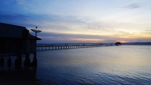 Pier over sea against sky during sunset