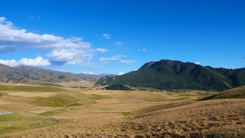 Scenic view of landscape and mountains against blue sky