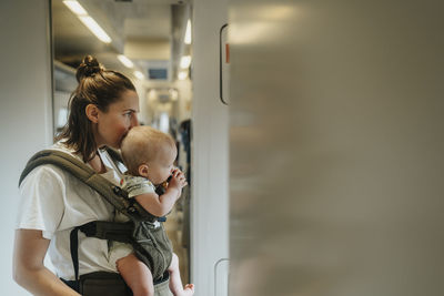 Mother with baby standing in train corridor