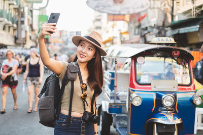 Full length of young woman using mobile phone in city