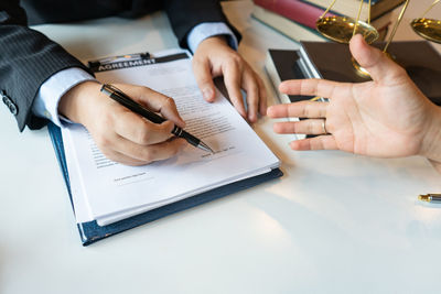 Cropped hands of insurance agent with client on desk