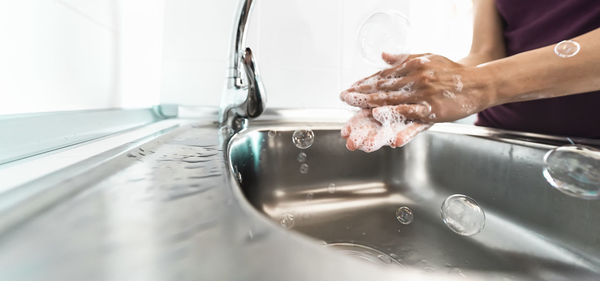 Midsection of person with reflection in water at home