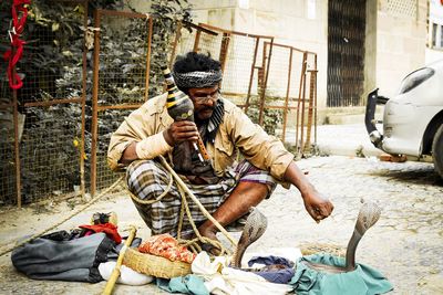 Man sitting with umbrella on street in city