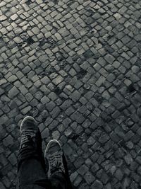 Low section of person standing on cobblestone street