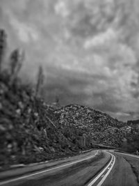 Road passing through landscape against cloudy sky
